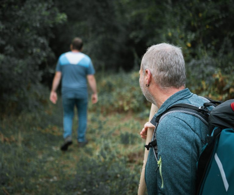 Naturcoaching Begleitung Zwei Wanderer im Wald, einer geht voraus, der andere schaut ihm nach.